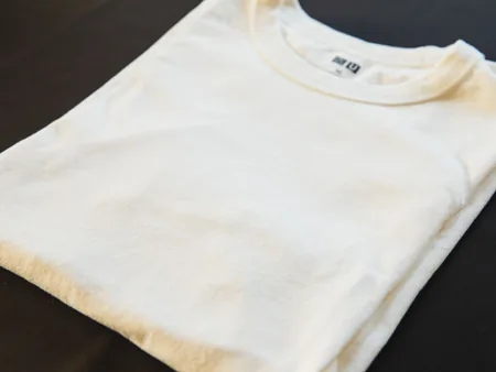 A folded white cotton T-shirt on a dark surface.