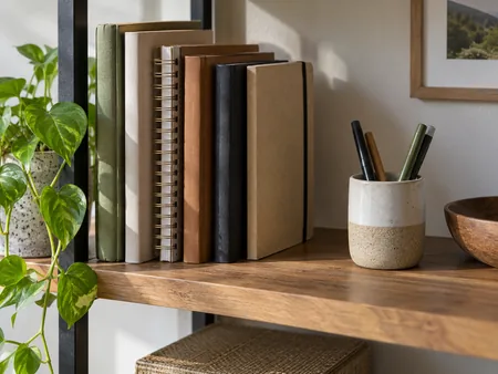 Plain notebooks stored upright on a dry indoor shelf with a small gap from the wall, no damp window or visible mould.
