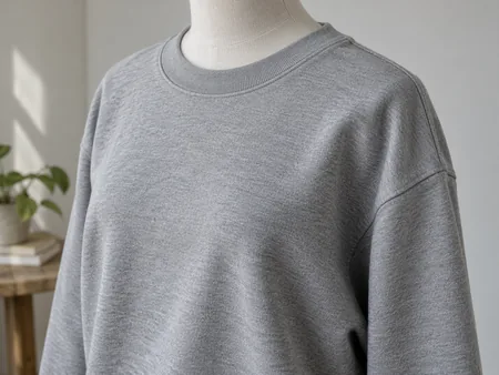A plain grey sweatshirt on a torso mannequin cropped below the neck, showing the shoulder seam sitting down the upper arm.
